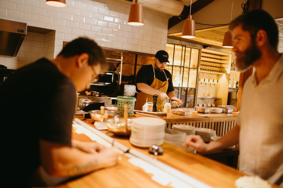 Chefs preparing food together in a busy restaurant kitchen