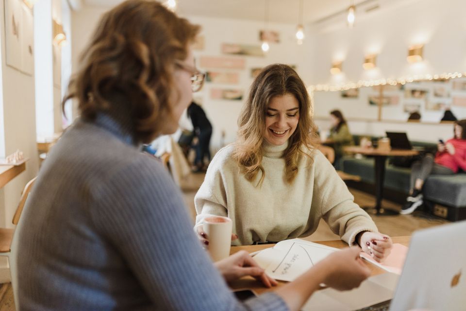 Two people discussing paperwork at a warm café table