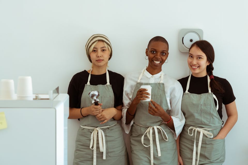 Three café coworkers standing together in aprons