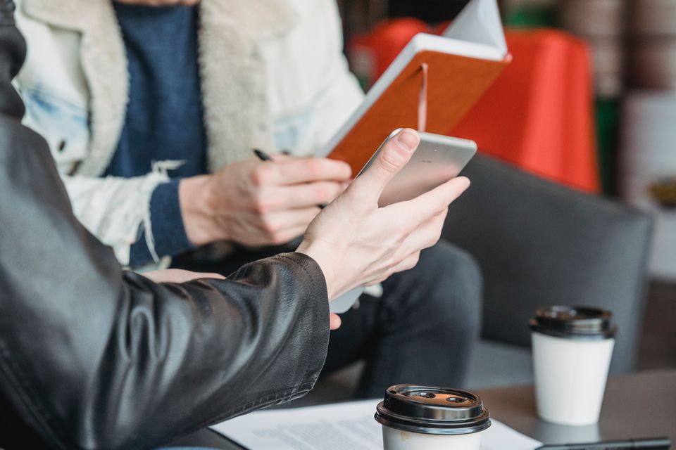 Two colleagues discussing work with a tablet and notebook at a café