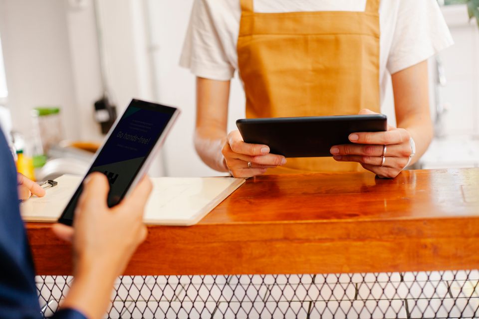 Café coworkers checking a smartphone and tablet at the counter