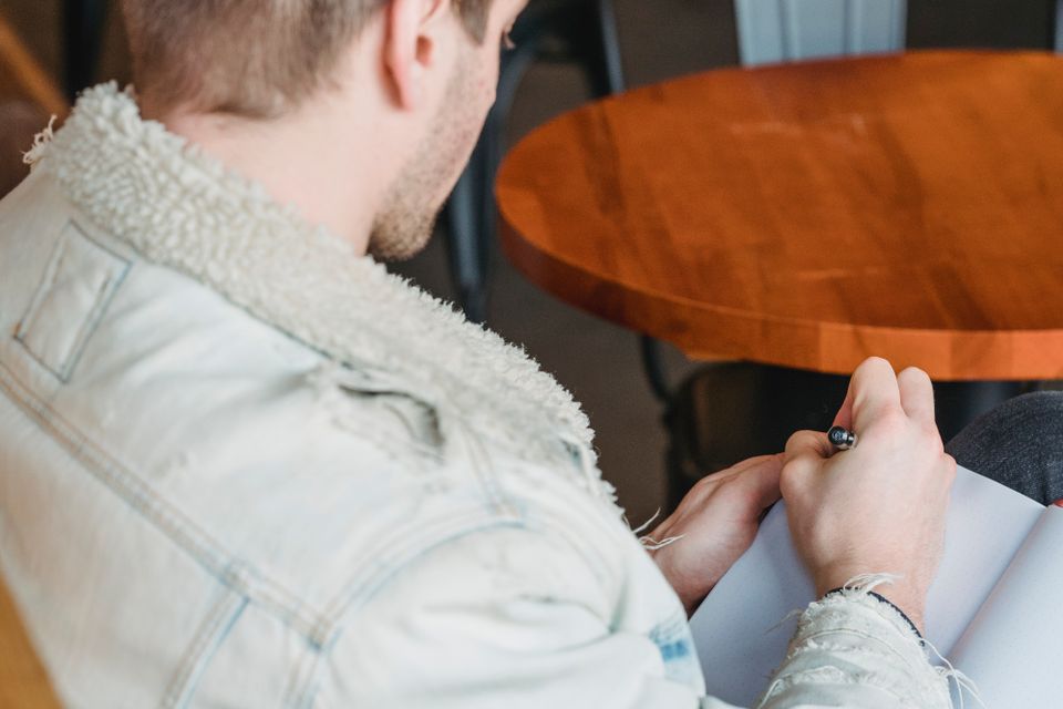 Person writing plans in a notebook at a café table